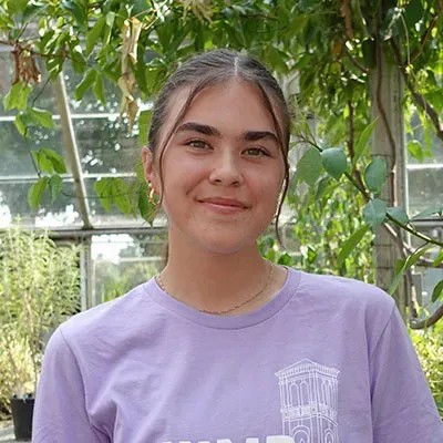 Jesika in light purple shirt with trees behind