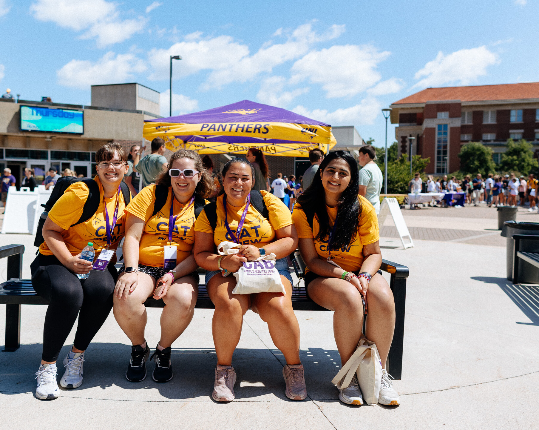 Four Cat Crew members sitting on bench outside the Union during the Student Organization Fair
