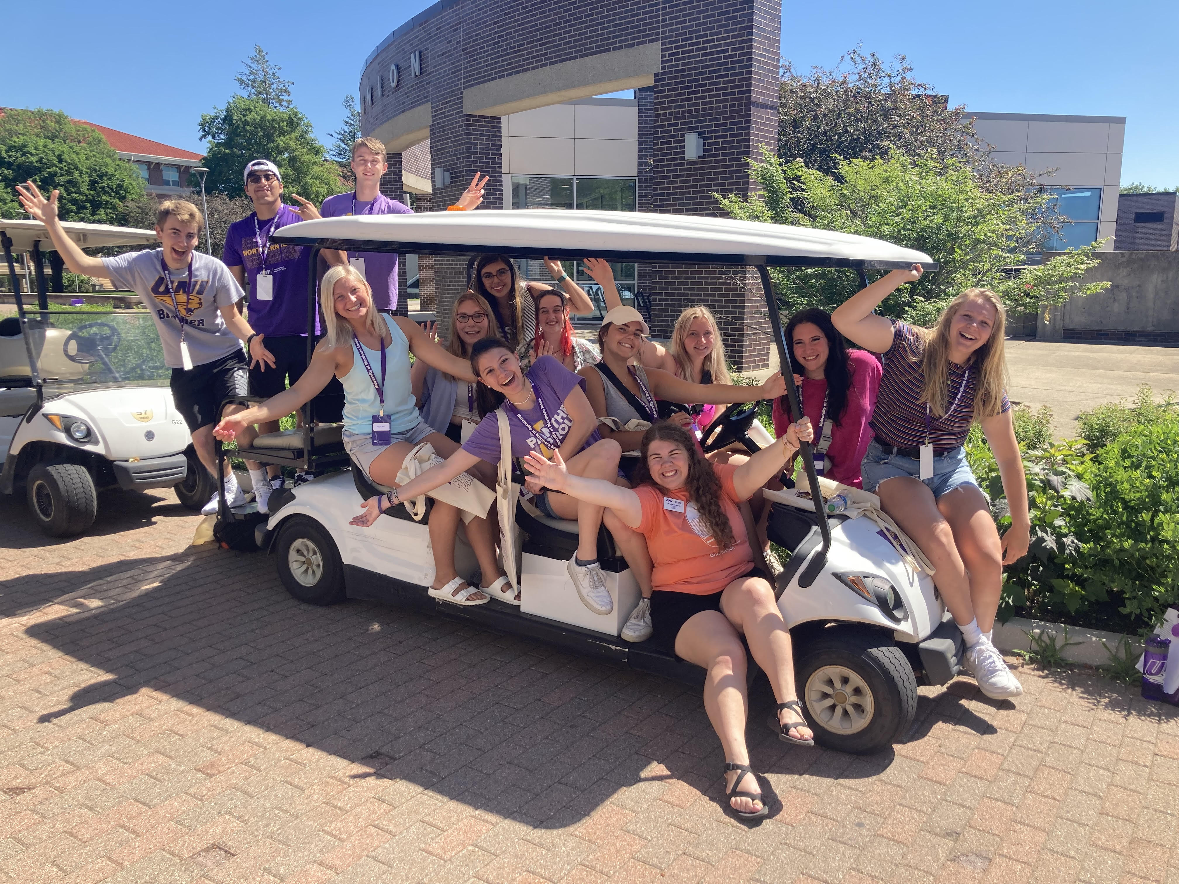 Orientation students taking staged photo on golfcart during orientation day. 