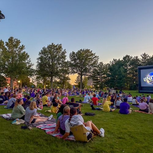 Students watching a movie at a field on campus.