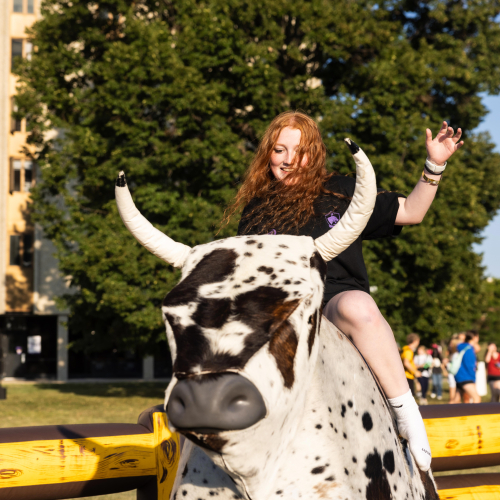 Student riding mechanical bull.